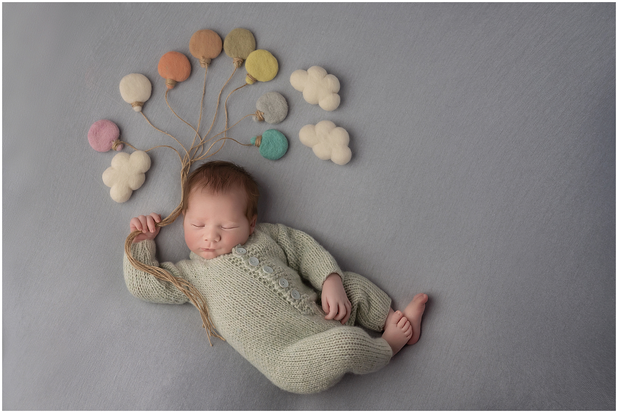 baby posed like floating in the sky with balloons and clouds