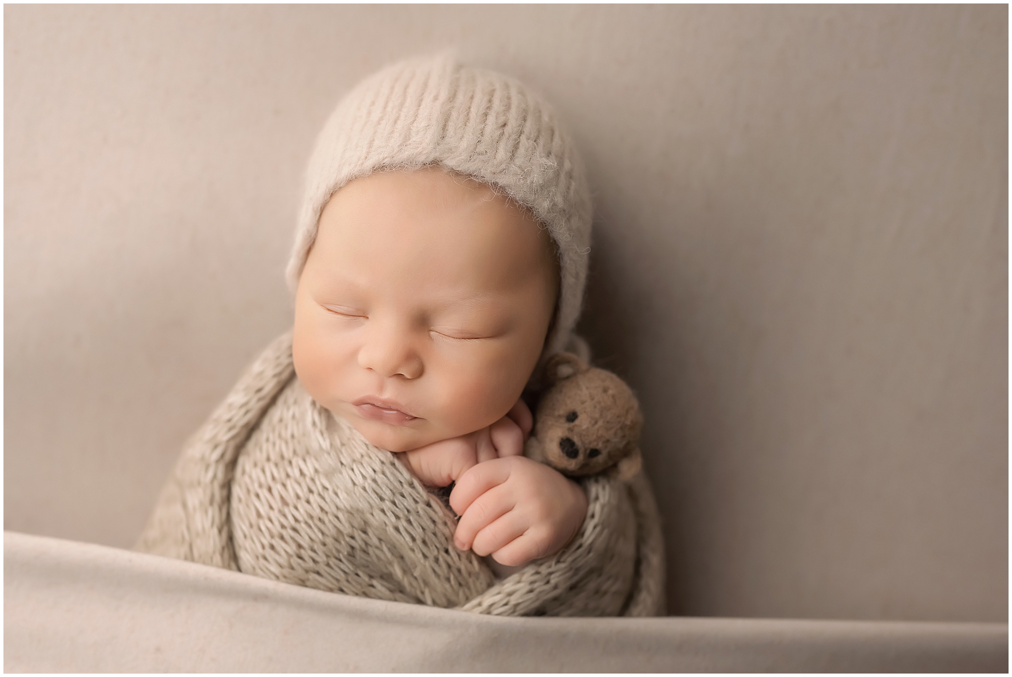 newborn baby boy hugging teddy bear