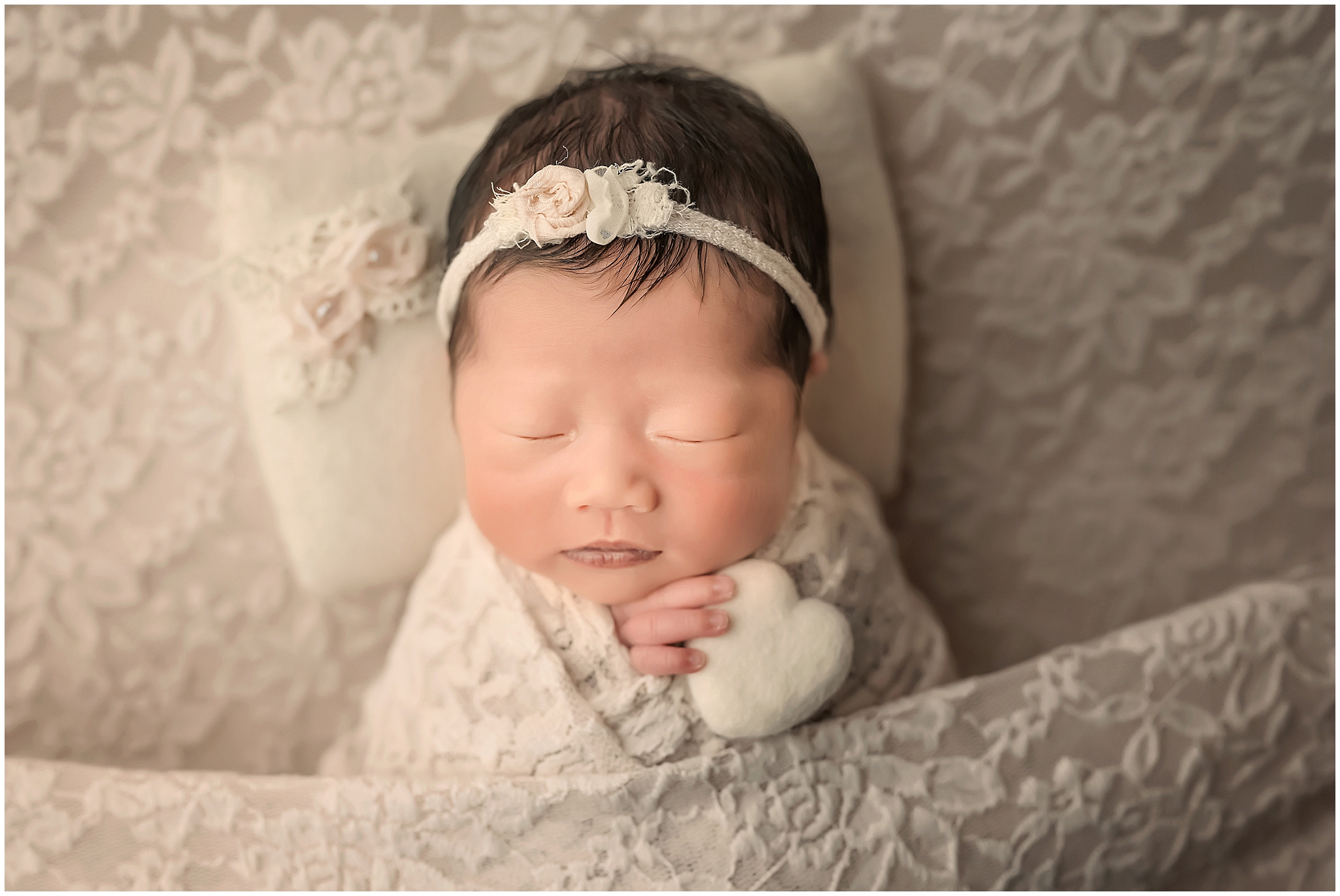 newborn baby holding a heart and sleeping during session at london ontario photography studio
