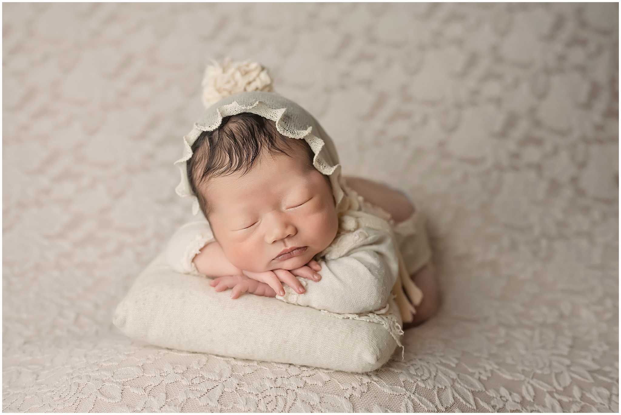 newborn baby resting on pillow during newborn session in London Ontario photography studio