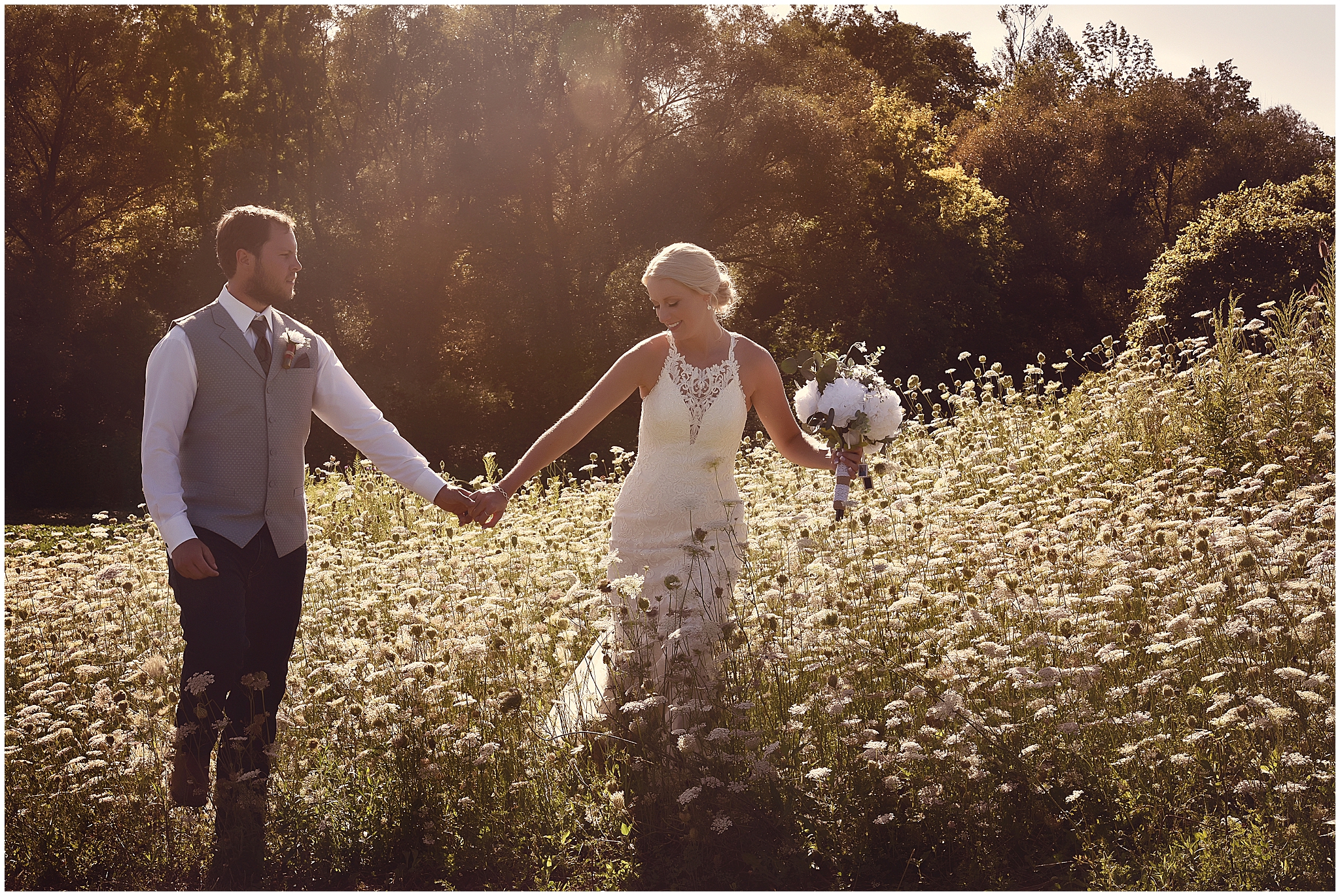 bride and grooom walking through field of wildflowers