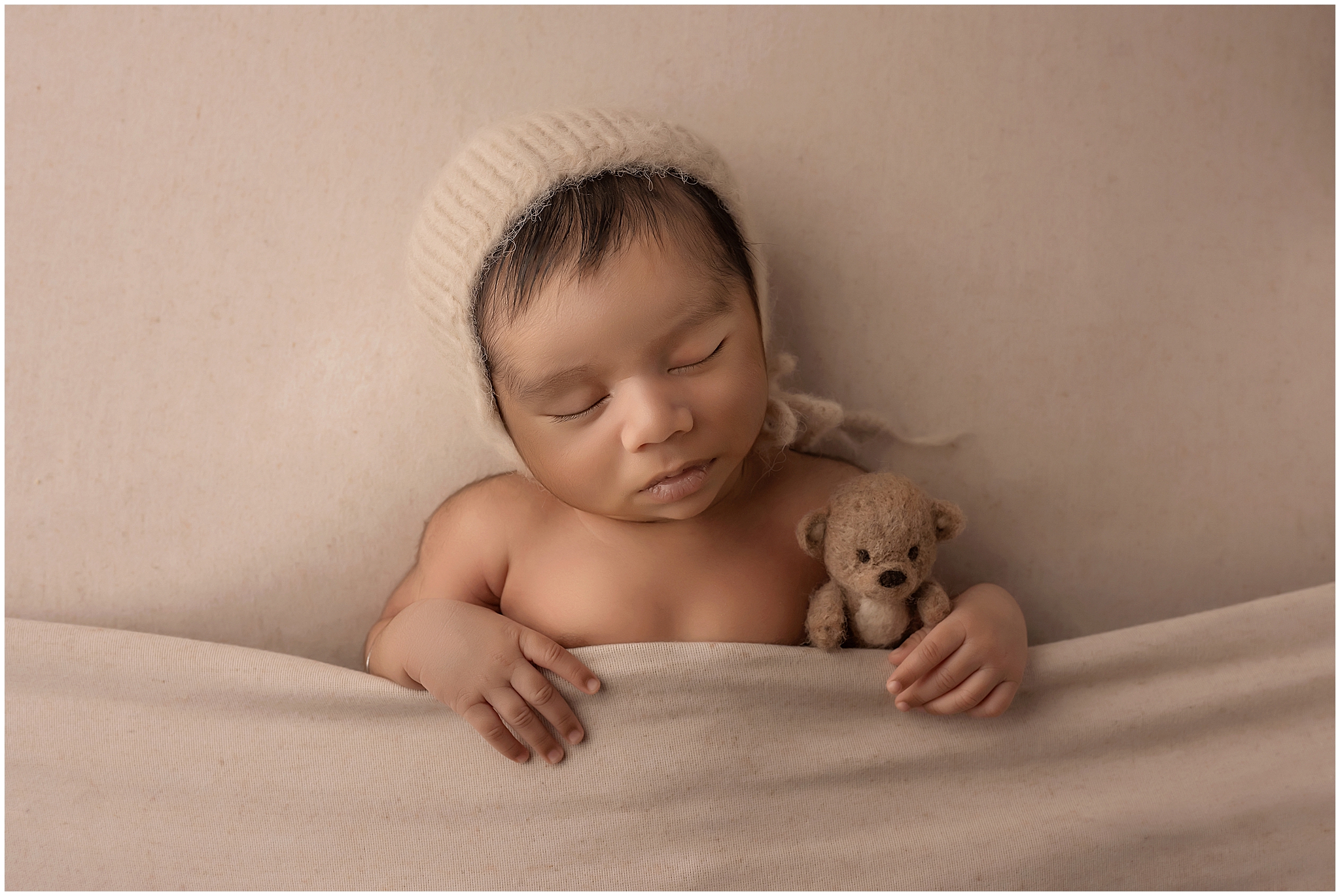 newborn baby boy sleeping with teddy bear in professional photography studio in london ontario