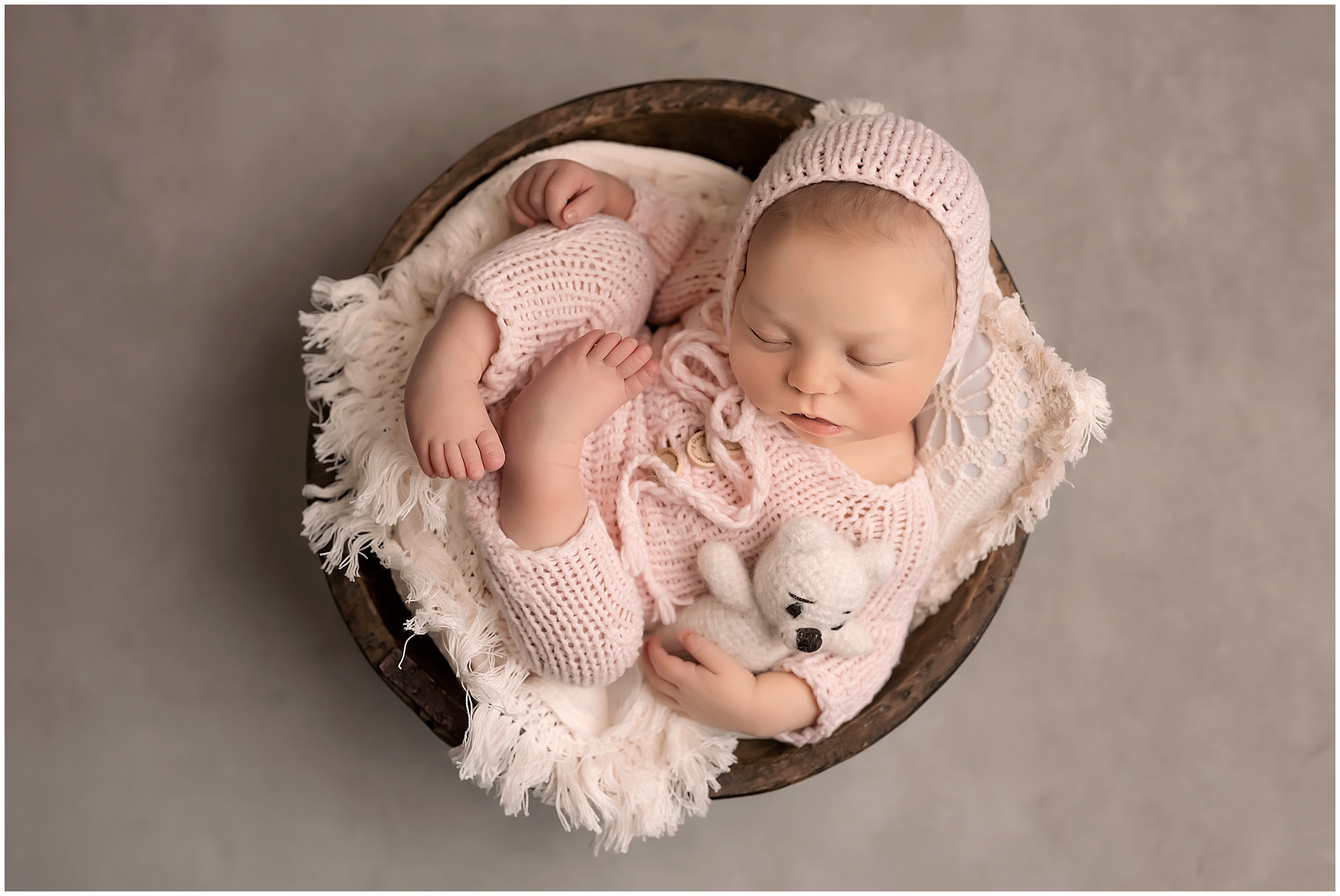 baby sleeping in bowl holding teddy bear during newborn photography session in london ontario