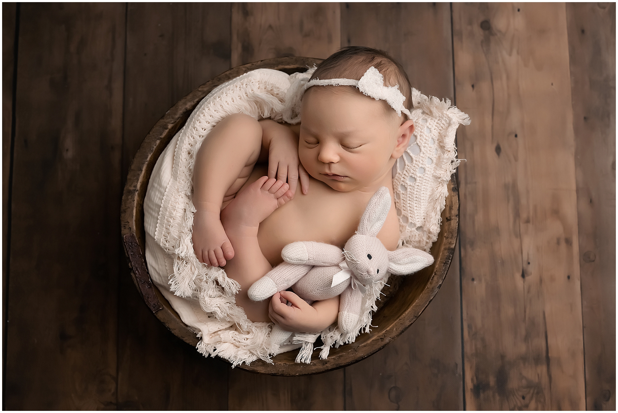 baby girl sleeping in bowl during newborn photography session at professional studio in london ontario