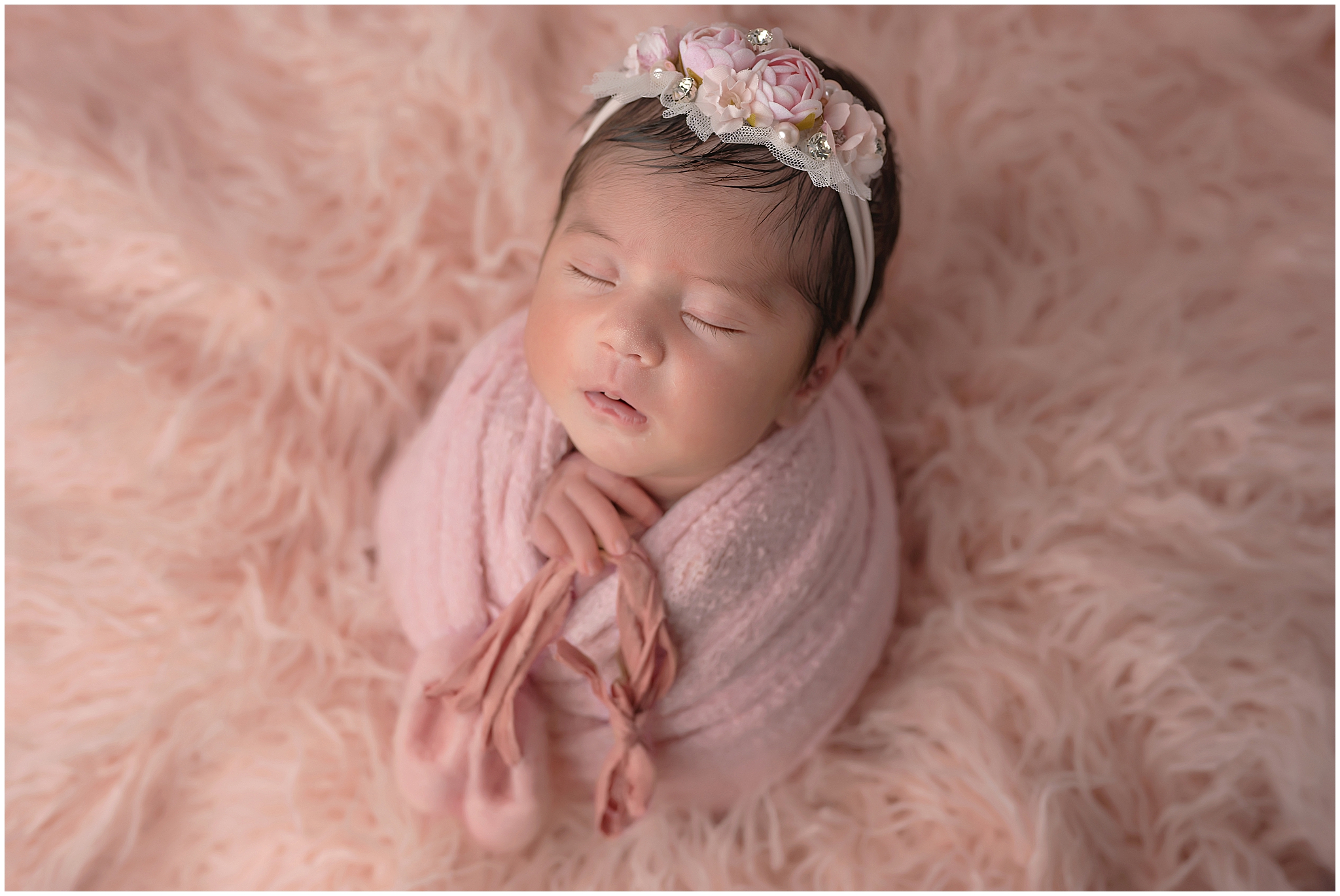 baby girl holding ballet slippers during newborn photography session at studio in london ontario