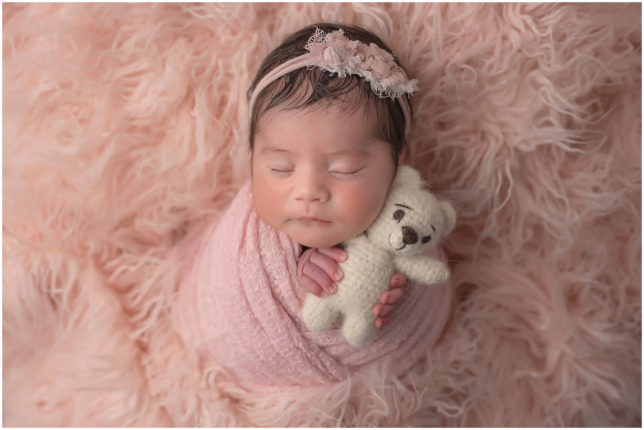 baby girl holding teddy bear during newborn photography session at studio in london ontario