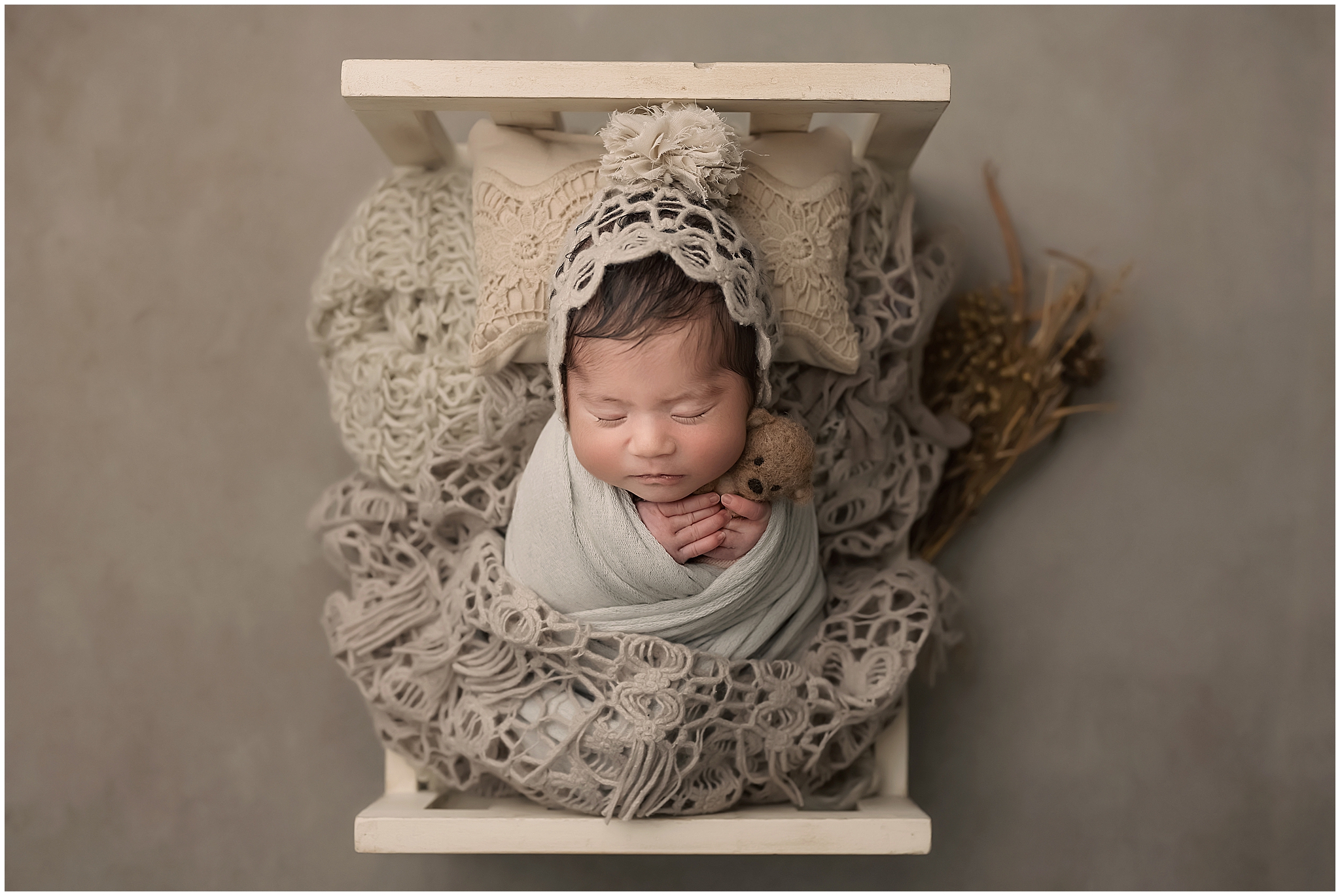 baby girl sleeping in tiny bed during newborn photography session in studio in london ontario