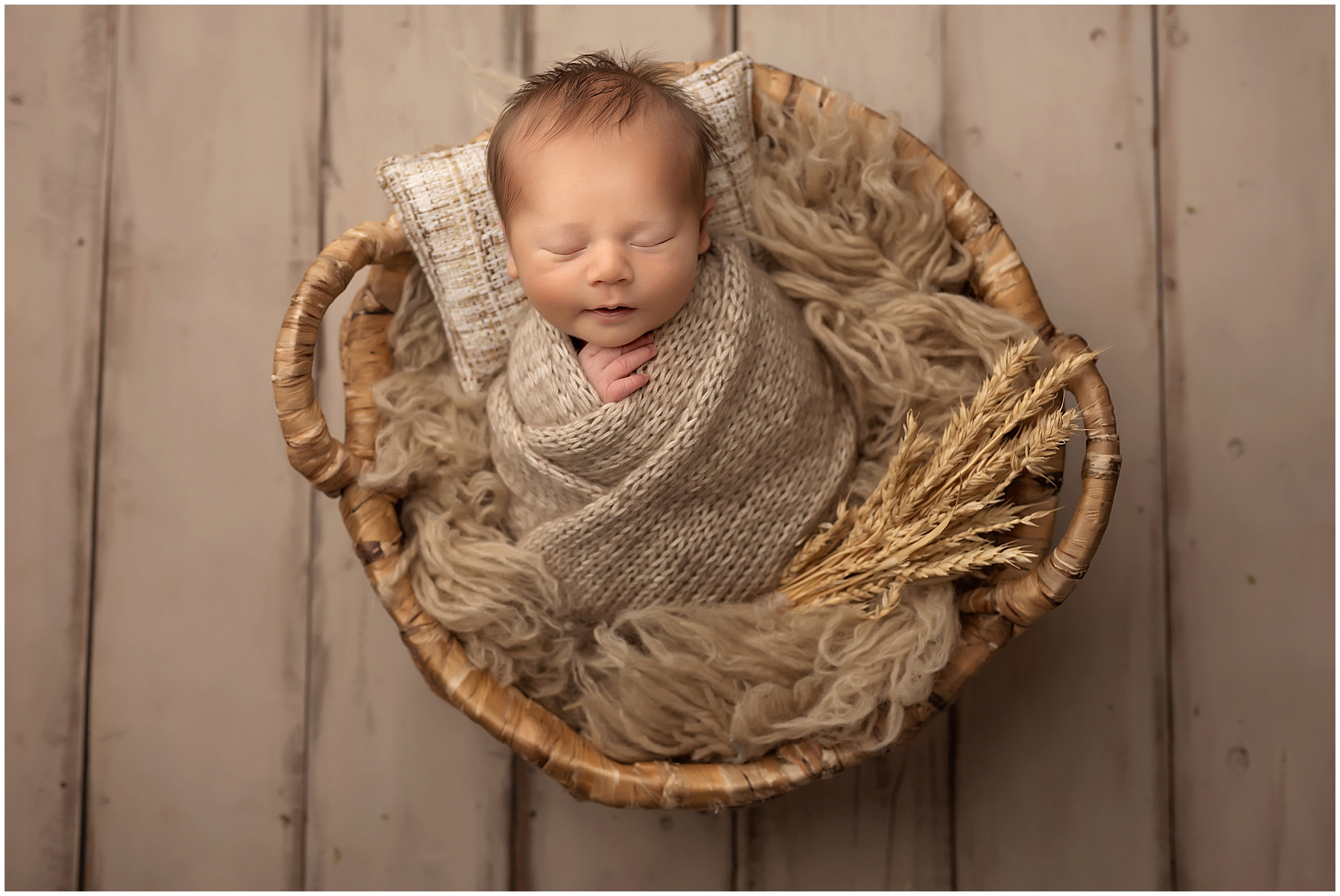 newborn baby boy wrapped and sleeping in basket during newborn photography session in London Ontario studio