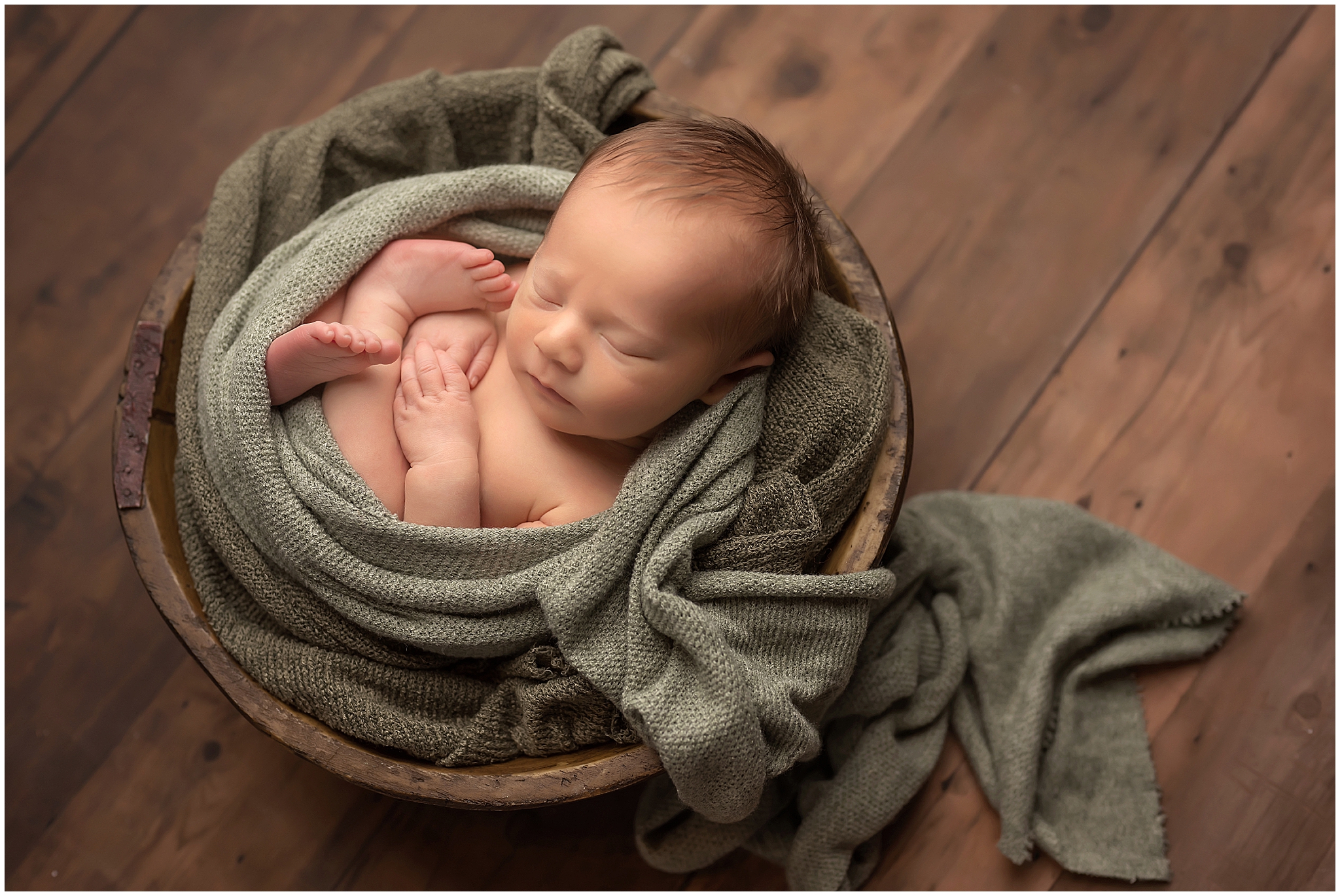 newborn baby sleeping in bowl during newborn photography session in London Ontario studio