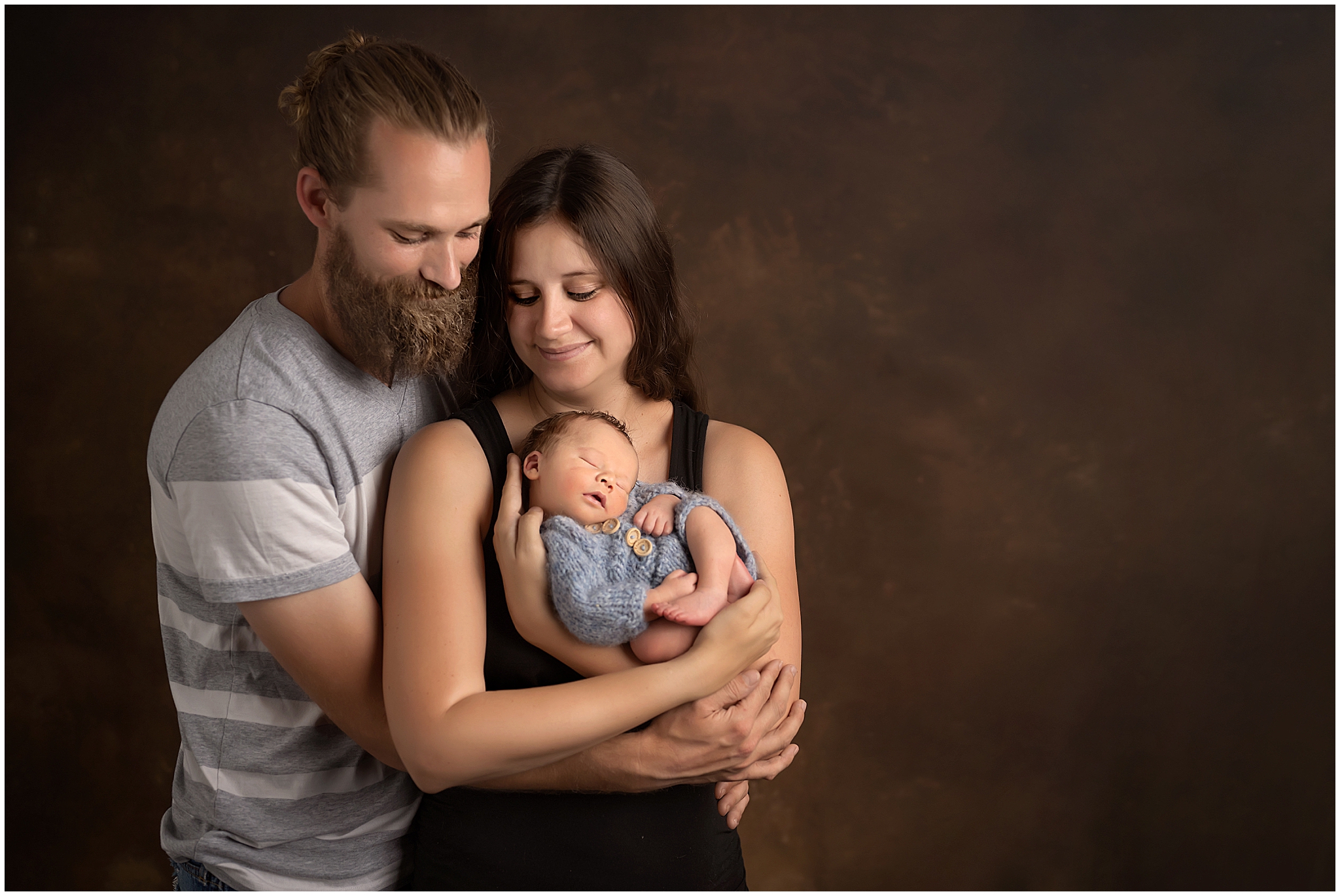 parents posing with newborn baby boy at professional photography studio in london ontario