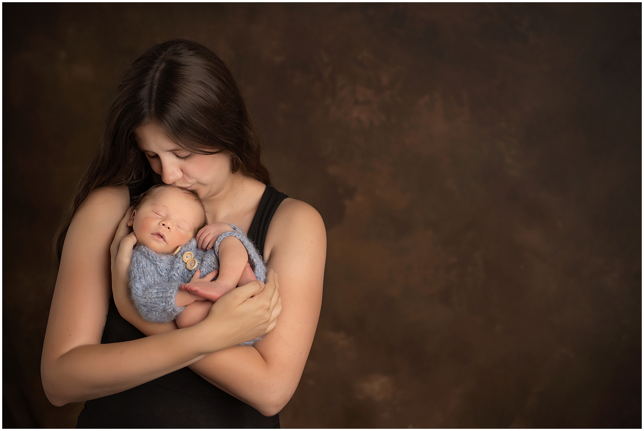 mom kissing and posing with newborn baby boy for professional photos in london ontario
