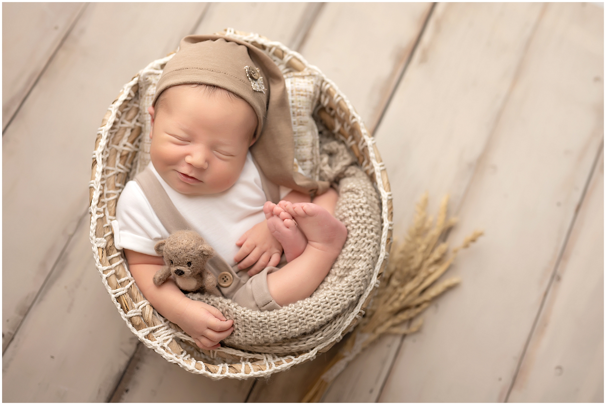 baby boy curled up in basket holding teddy bear during newborn session at studio in london, ontario