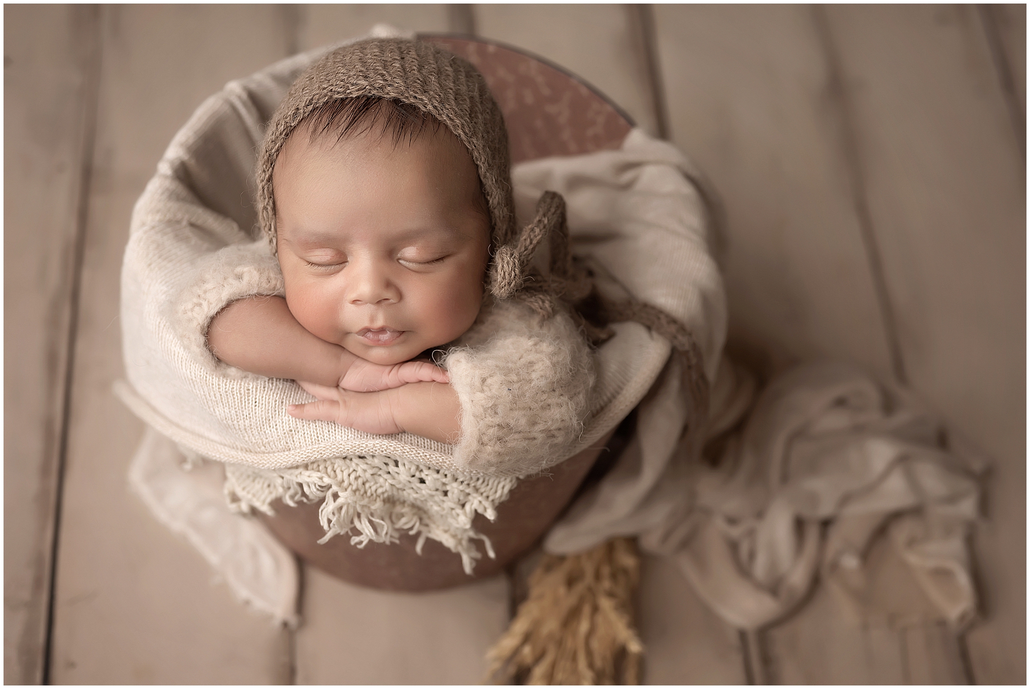 newborn baby posing in bucket with neutral colours  during newborn photography session at london ontario studio
