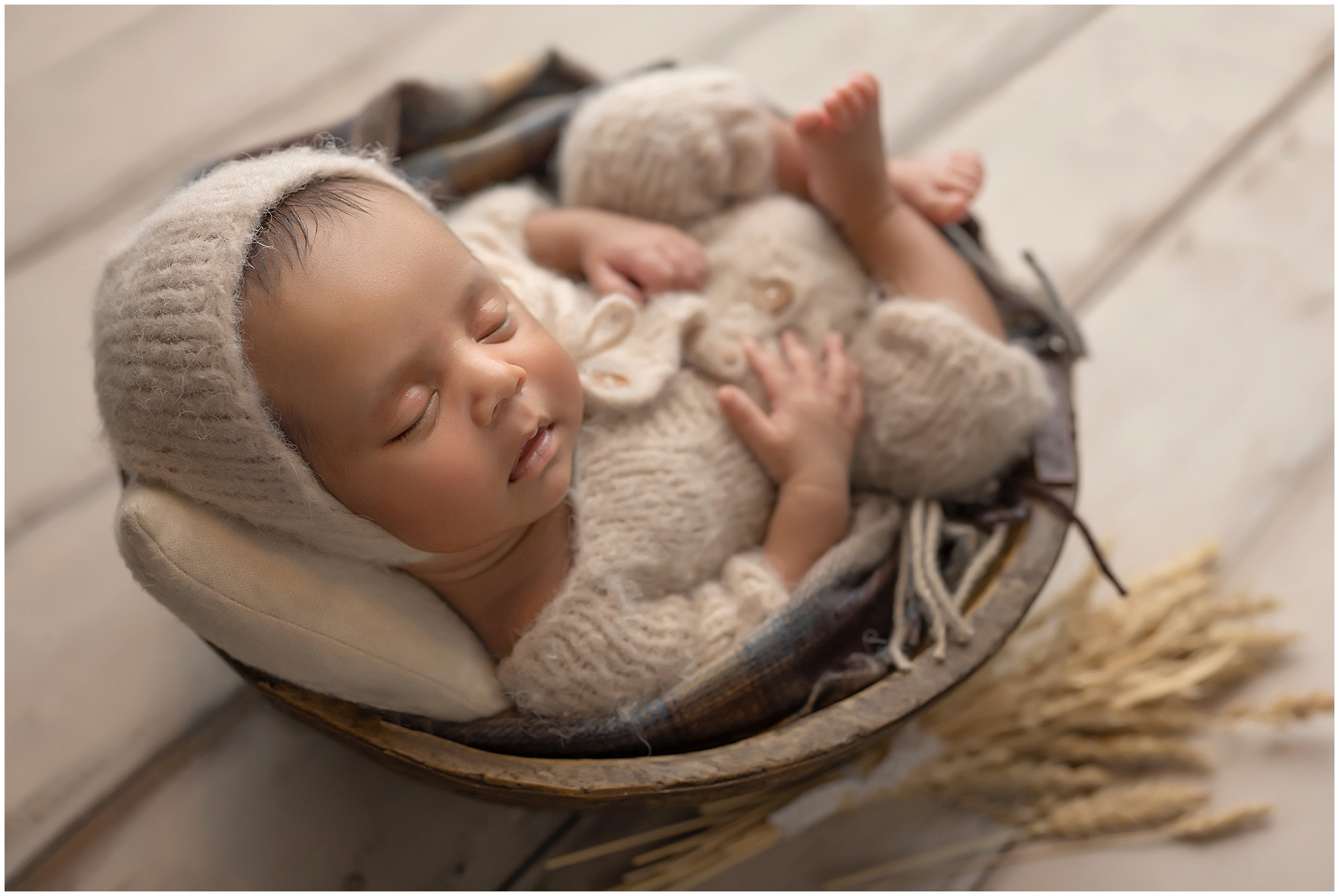 newborn baby sleeping in bowl with neutral colours  during newborn photography session at london ontario studio