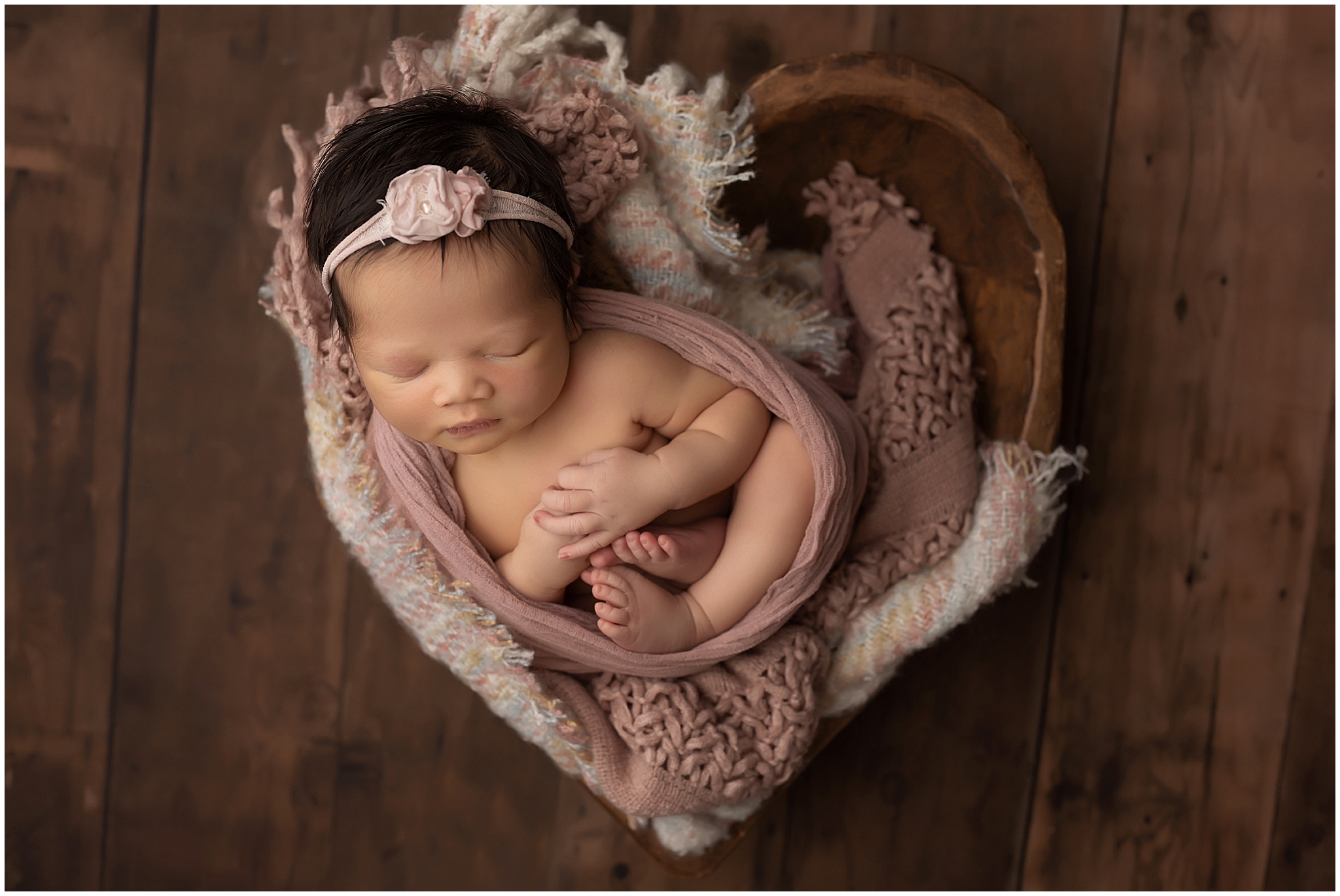 newborn baby sleeping in heart shaped bowl during photography session at london studio