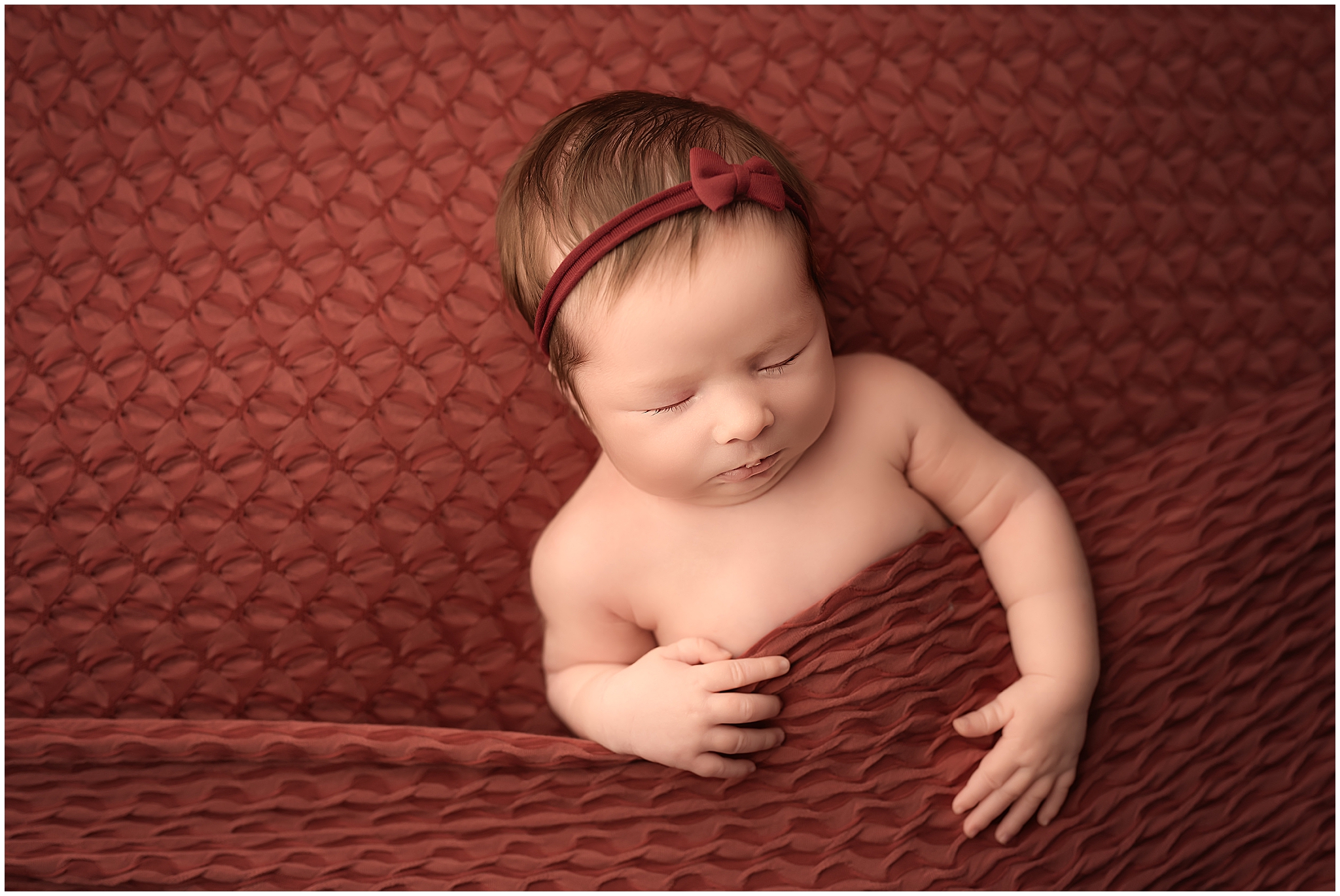 newborn baby girl sleeping on red backdrop at photography studio in london ontario