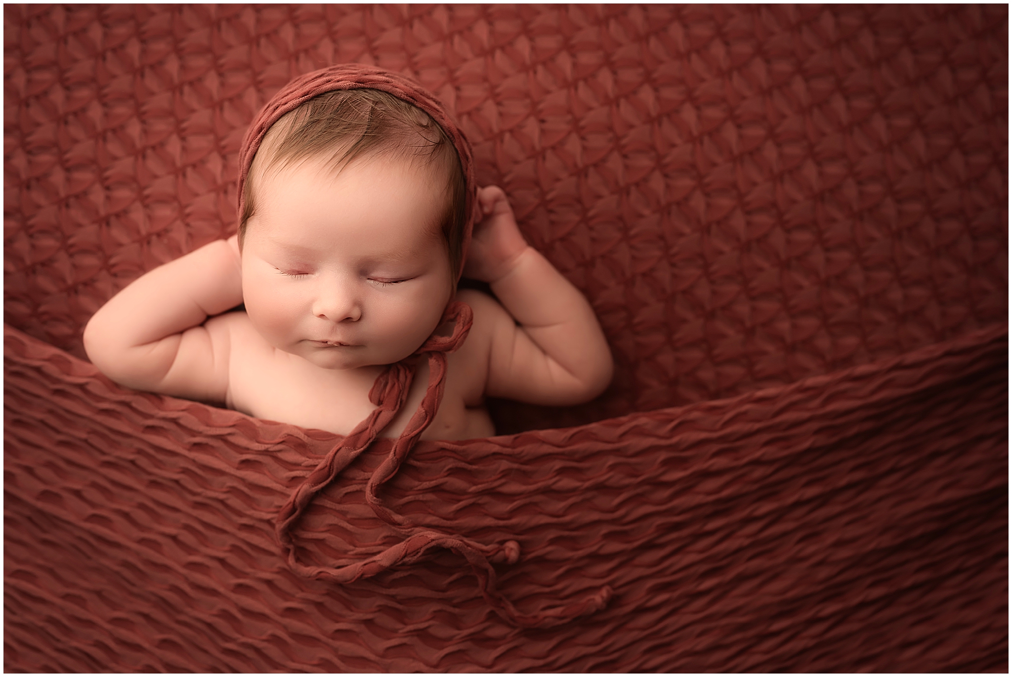 newborn baby girl sleeping on red backdrop during newborn session at london ontario studio