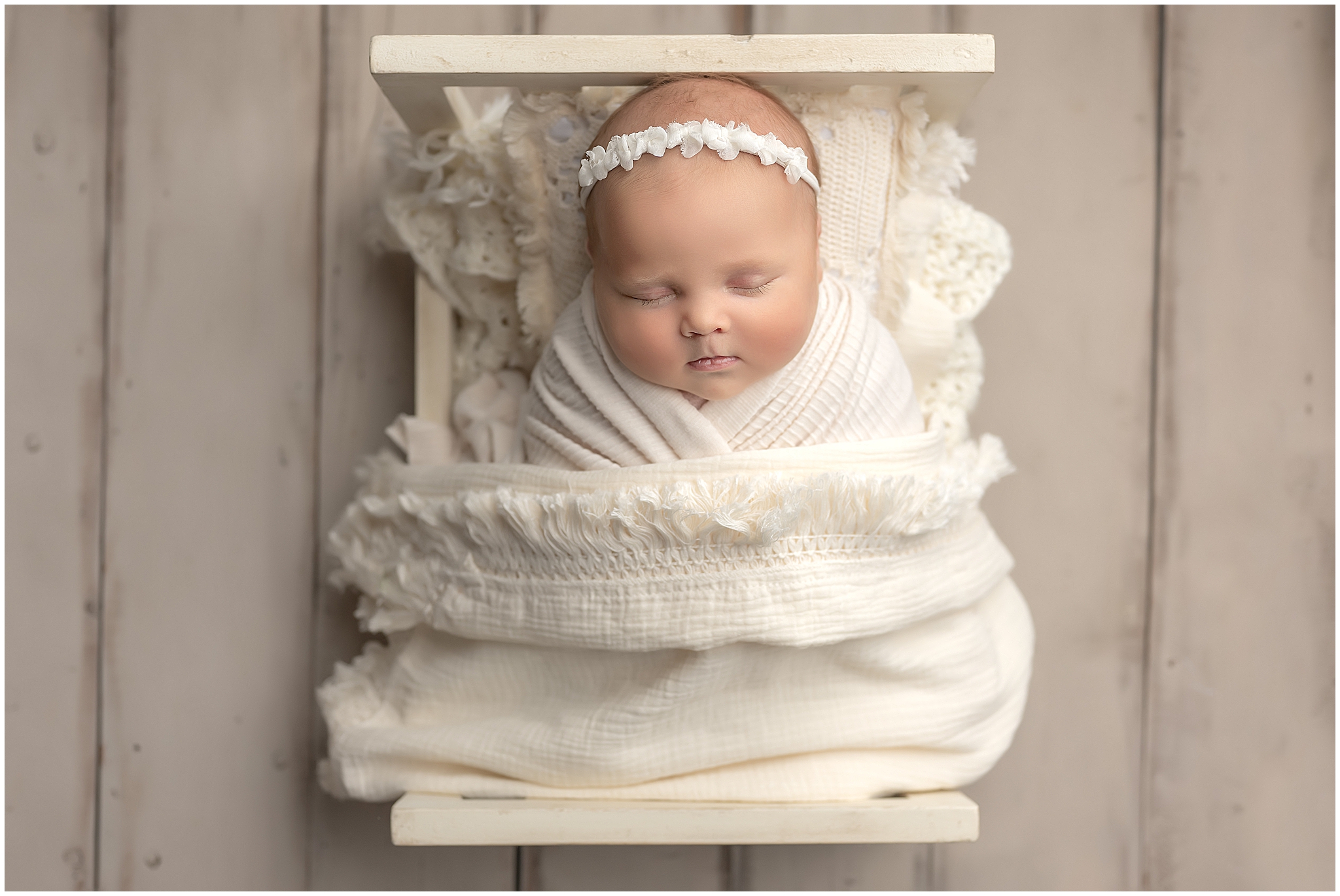 baby girl wrapped and sleeping on a tiny bed during newborn photography session in london ontario 
